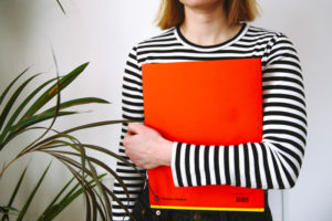 adult female student holding red folder