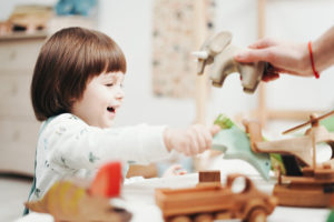 Child Playing With Green Plastic Toy