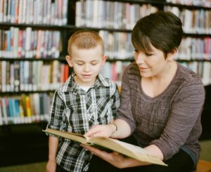 female teacher working with young male student in the library