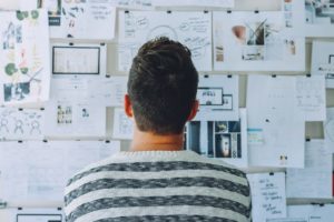 student standing in front of board with charts, graphs, data 