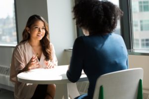 two female adults talking at a table