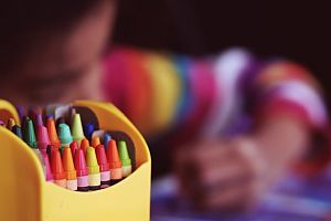 small child coloring with crayons in the foreground