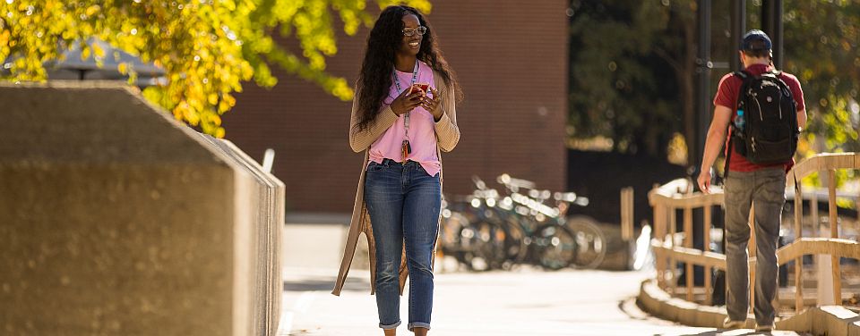 student on sidewalk in front of Bailey Education Complex