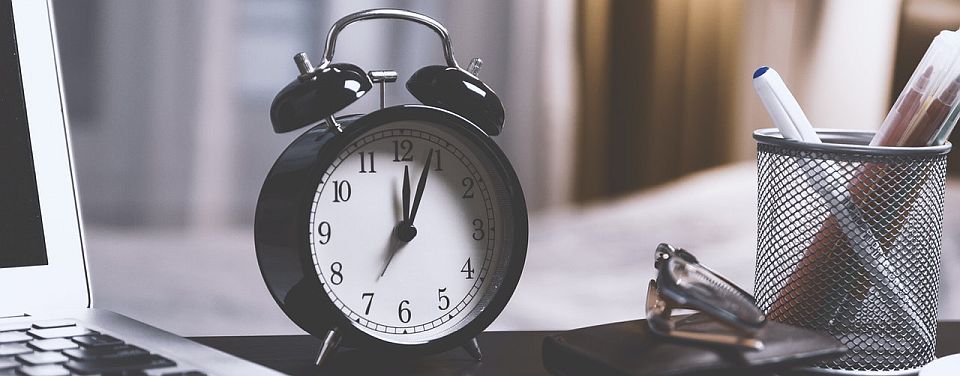 two bell alarm clock sitting on desk with laptop and office supplies