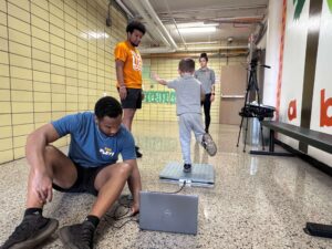 Researchers recording a child's balance and movement test in a school hallway