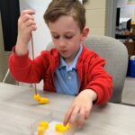 Child completing a fine motor task with small pegs at a table