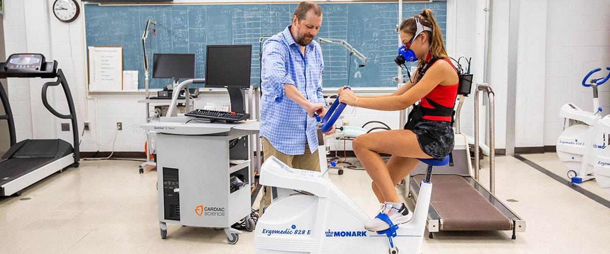 Researcher helping a student on a stationary bike during an exercise physiology test