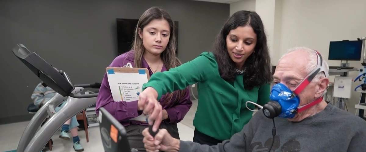 Researchers guiding an older adult through an exercise test while he wears a metabolic mask