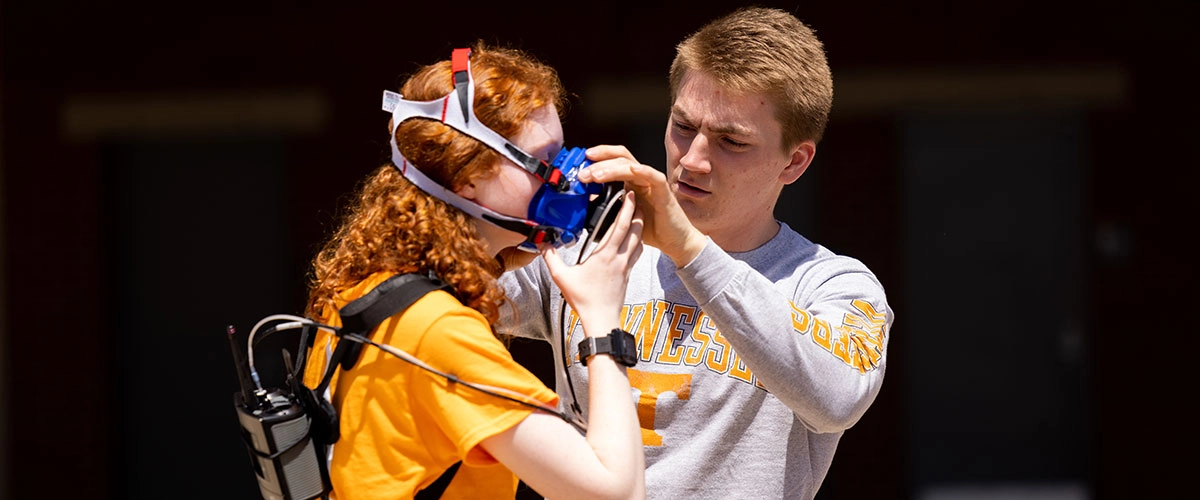 Student fitting a metabolic mask and portable monitor on a research participant