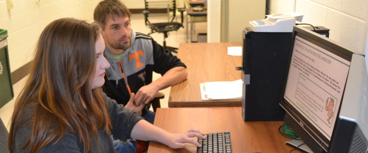 Researcher and student working at a computer during a motor behavior study