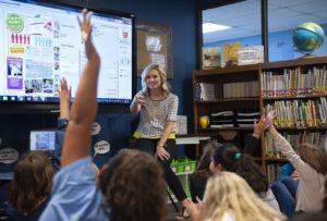 Lori Farley with students raised hand photo