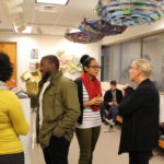 faculty and students talking intern art show