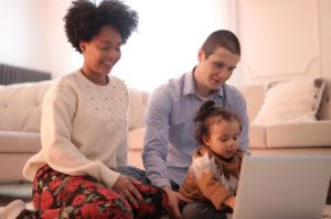 family sitting at laptop with small child