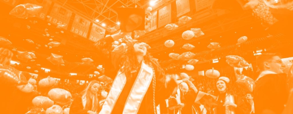 Graduates throwing caps and balloons in Thompson Boling Arena