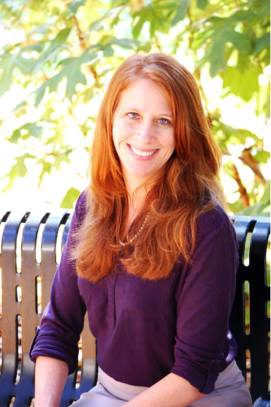 Tara Moore sitting on a bench wearing a purple blouse