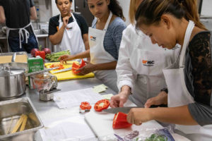 Group of female students cutting up bell peppers to be used in culinary medicine class