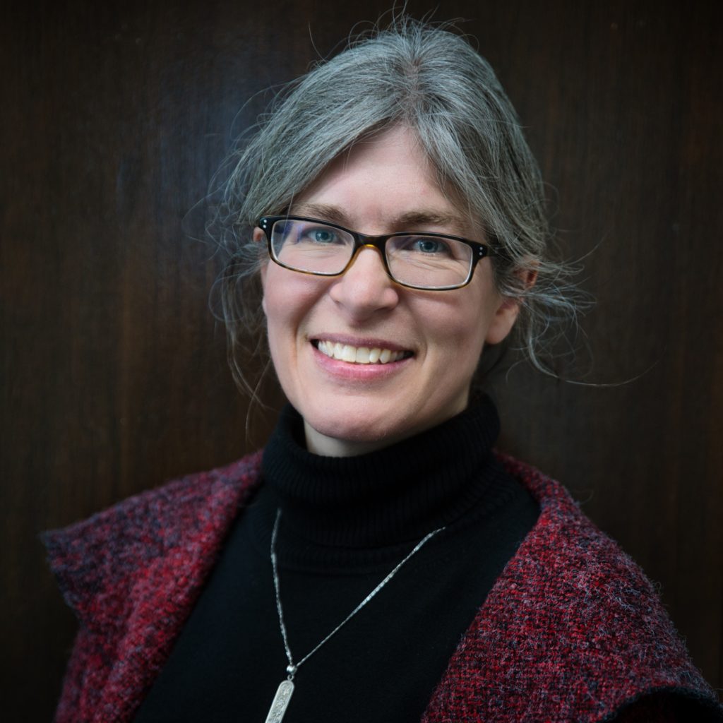 Photo of Melissa Hensen-Petrick, a fair complexion female with glasses and grey hair. Melissa is smiling in the photograph.