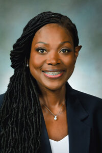 Portrait photo of Kimberly Hill. She has dark skin and black hair. She is smiling in the photograph. 