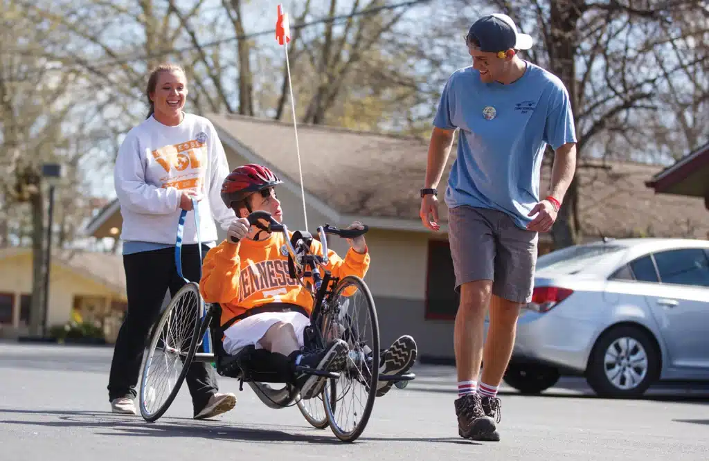 a student in a wheelchair is assisted by two other students at the University of Tennessee