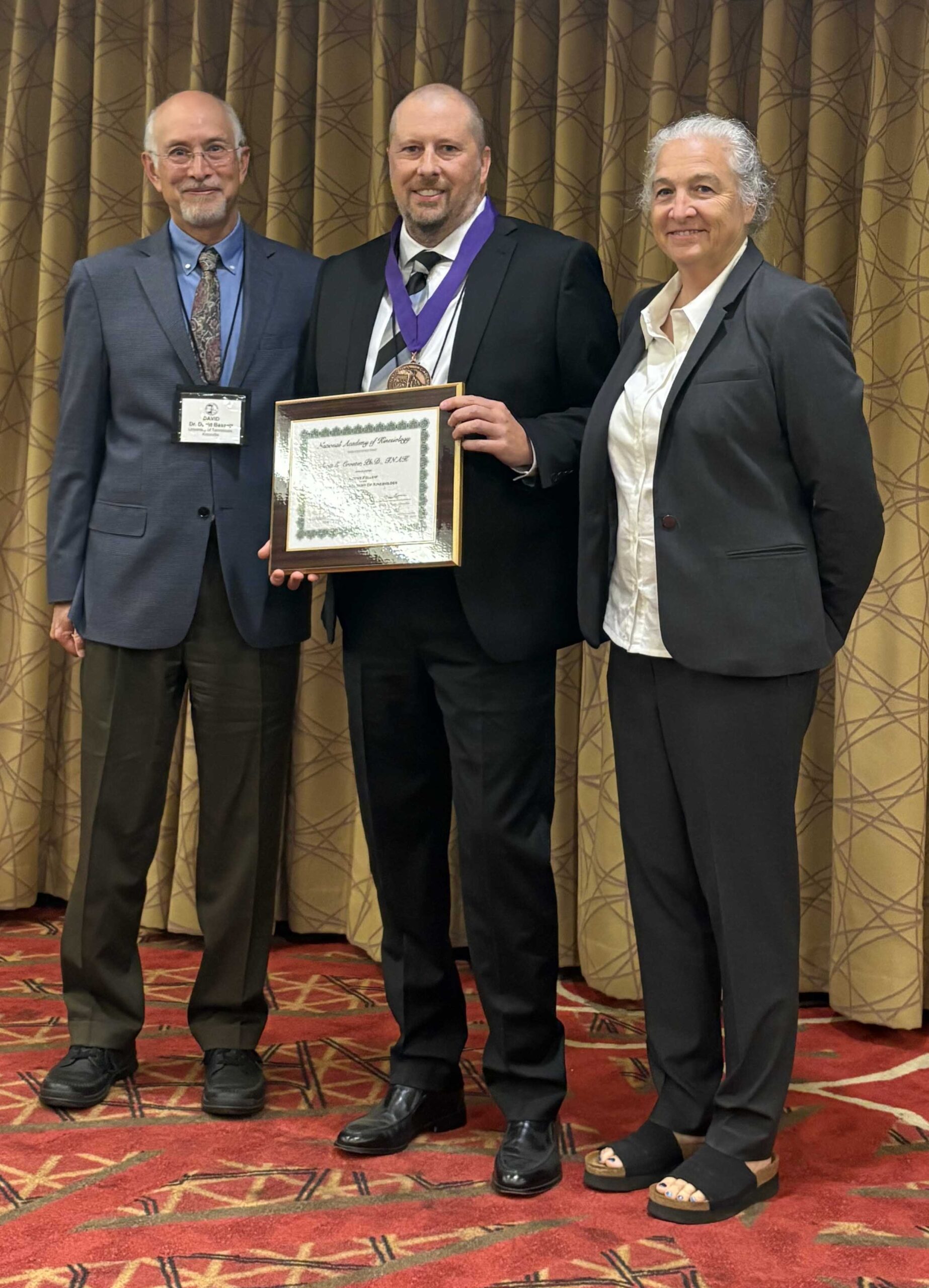 Scott Crouter standing and holding fellowship certificate